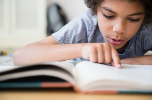 Mixed race boy reading book at desk